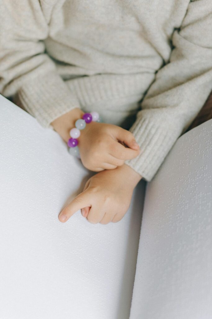 A child uses their fingers to read a book in braille, emphasizing touch and learning.
