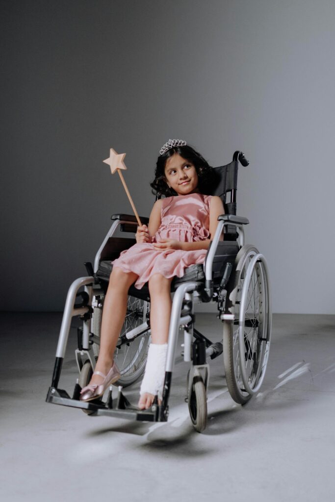Charming girl smiling in a wheelchair with magic wand and tiara, symbolizing joy and resilience.